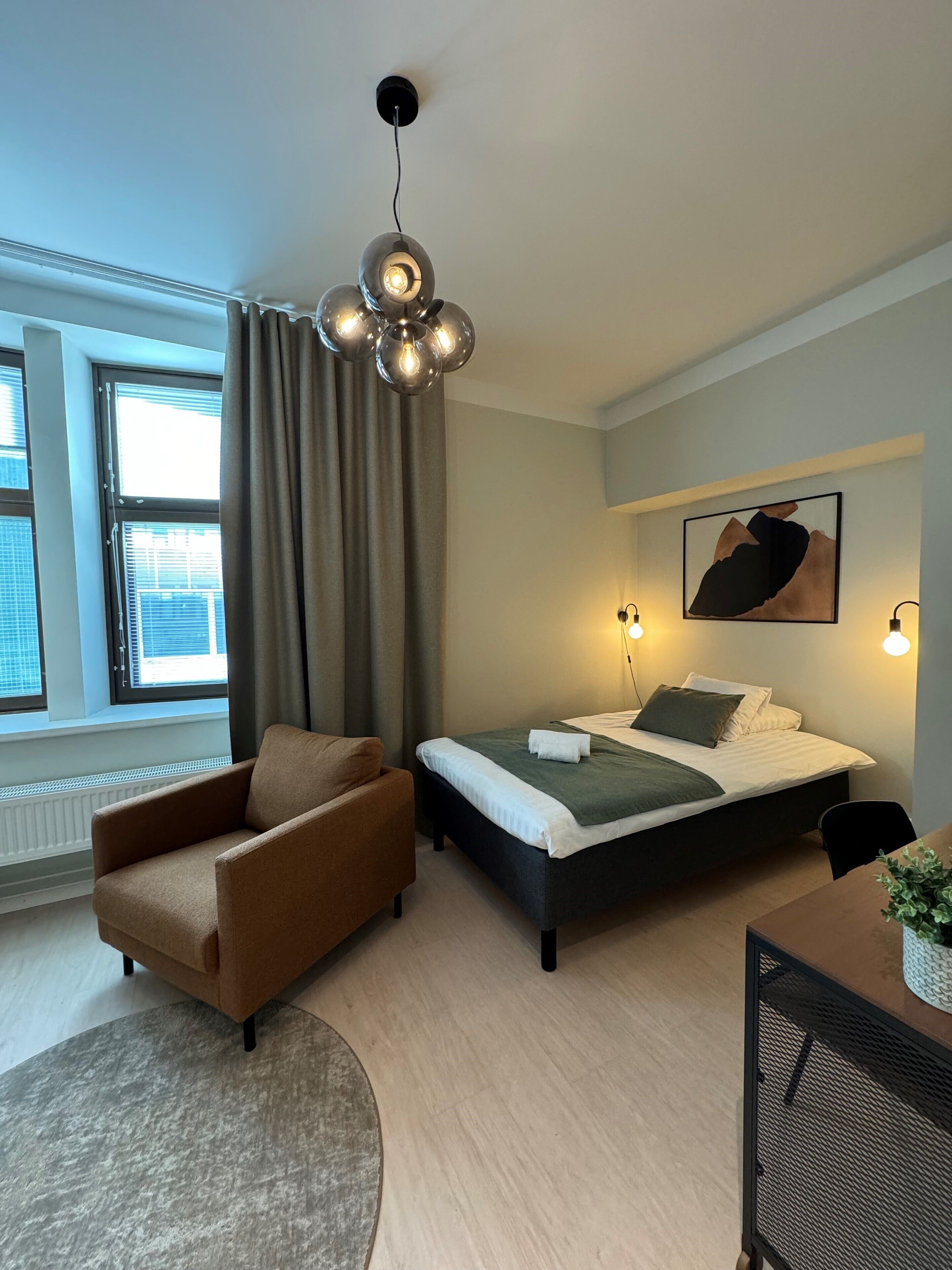 Un dormitorio moderno con una cama, un sillón marrón, un tapete redondo y una lámpara en el techo.