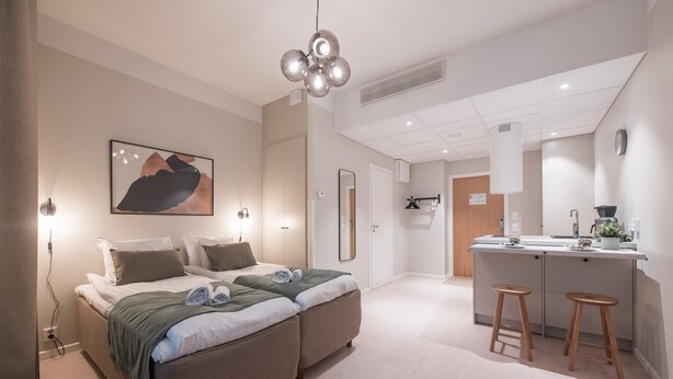 A modern hotel room with a large bed, a small kitchenette, and a bathroom visible in the background. - Forenom Aparthotel Tampere Kauppakatu (Tampere)