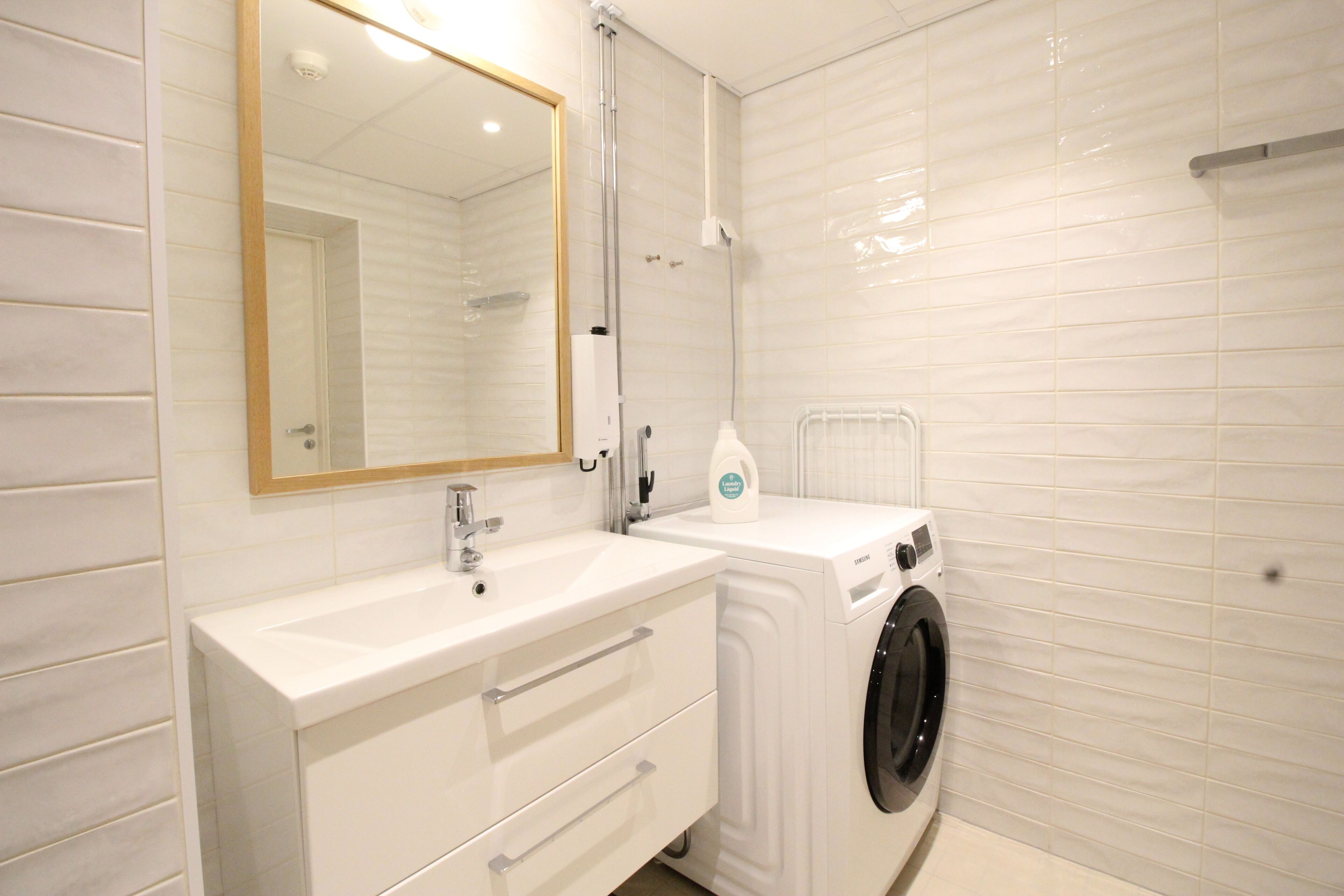 Une salle de bain moderne avec un lavabo blanc, un miroir et un lave-linge.