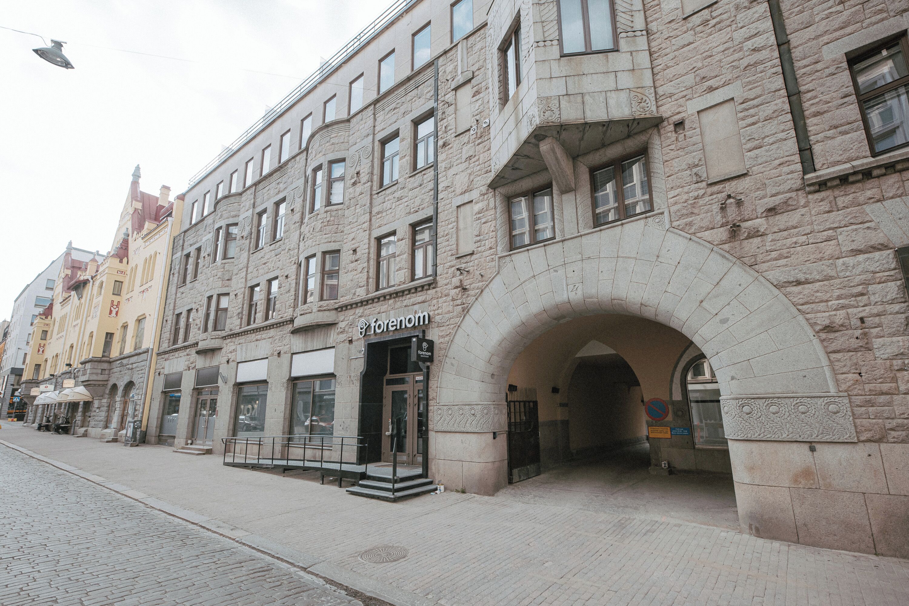 A historic building with a stone facade, a prominent archway entrance, and a storefront with a sign.