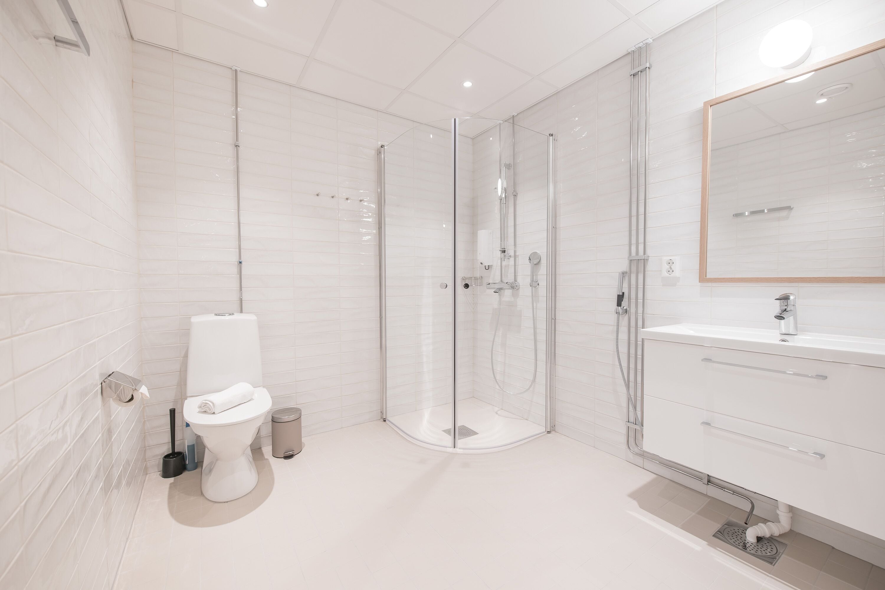 Un baño moderno con ducha envuelta en vidrio, inodoro blanco y tocador con espejo.