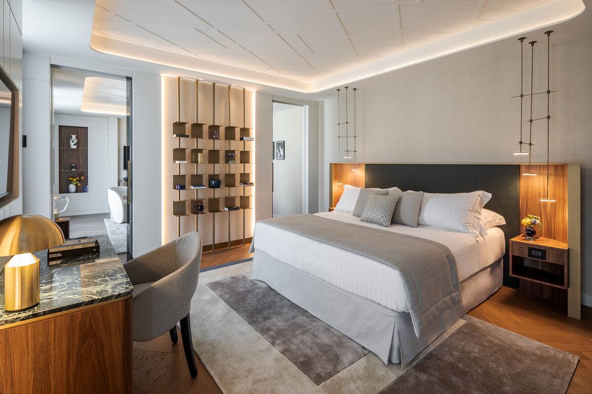 Ein modernes Schlafzimmer mit einem großen Bett, Nachttischen, einem Schreibtisch und einem Sessel.