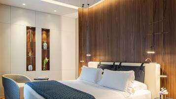 Una camera da letto moderna con un letto grande, un comodino, una sedia ed scaffali a incasso con oggetti decorativi.