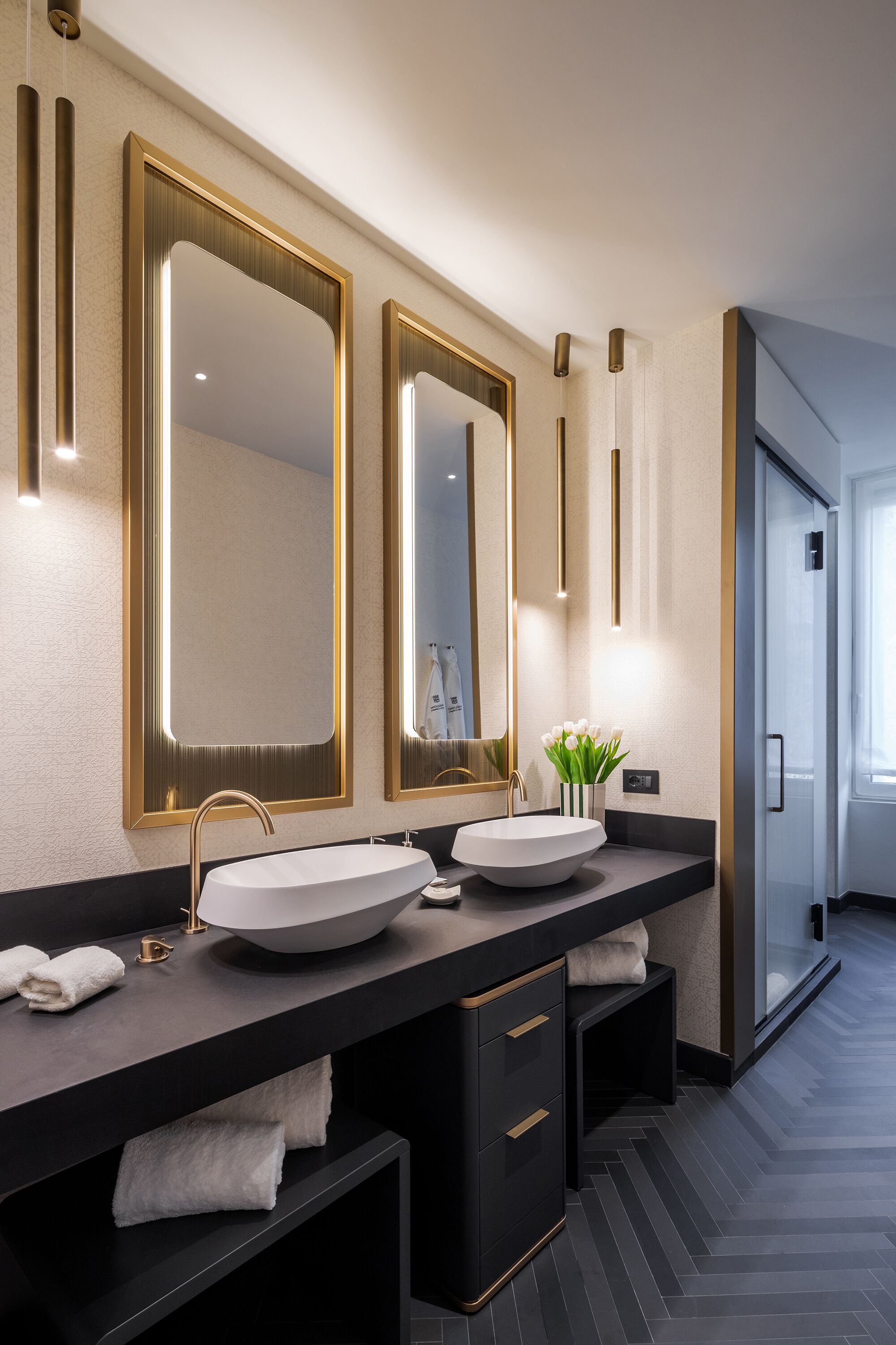 A modern bathroom with a large mirror, two sinks, and a towel rack.