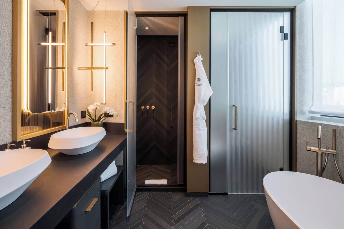 Ein modernes Badezimmer mit zwei Waschbecken, einem großen Spiegel und einer bodengleichen Dusche.