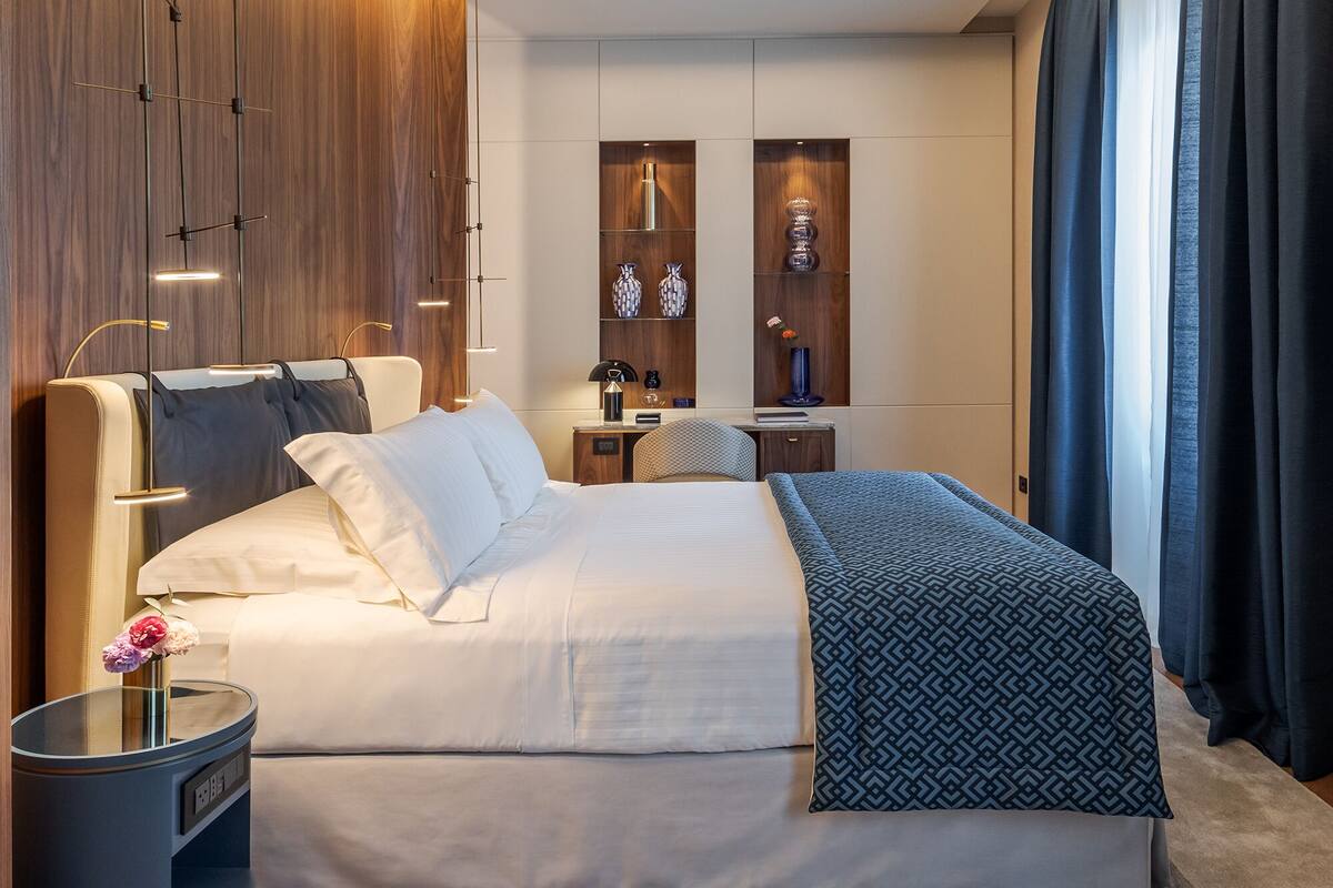 Ein modernes Schlafzimmer mit einem großen Bett, Nachttischen, einem einbaubaren Kleiderschrank und einer Deckenleuchte.