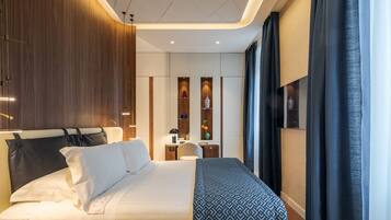 A modern hotel room with a large bed, a desk, and a wardrobe.