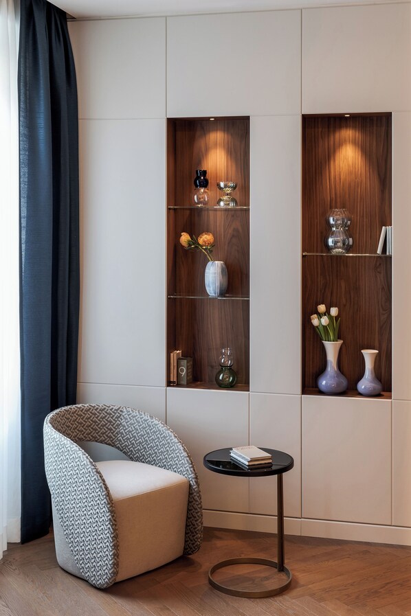A modern living room with a curved chair, a small round table, and built-in wooden shelves with decorative items.