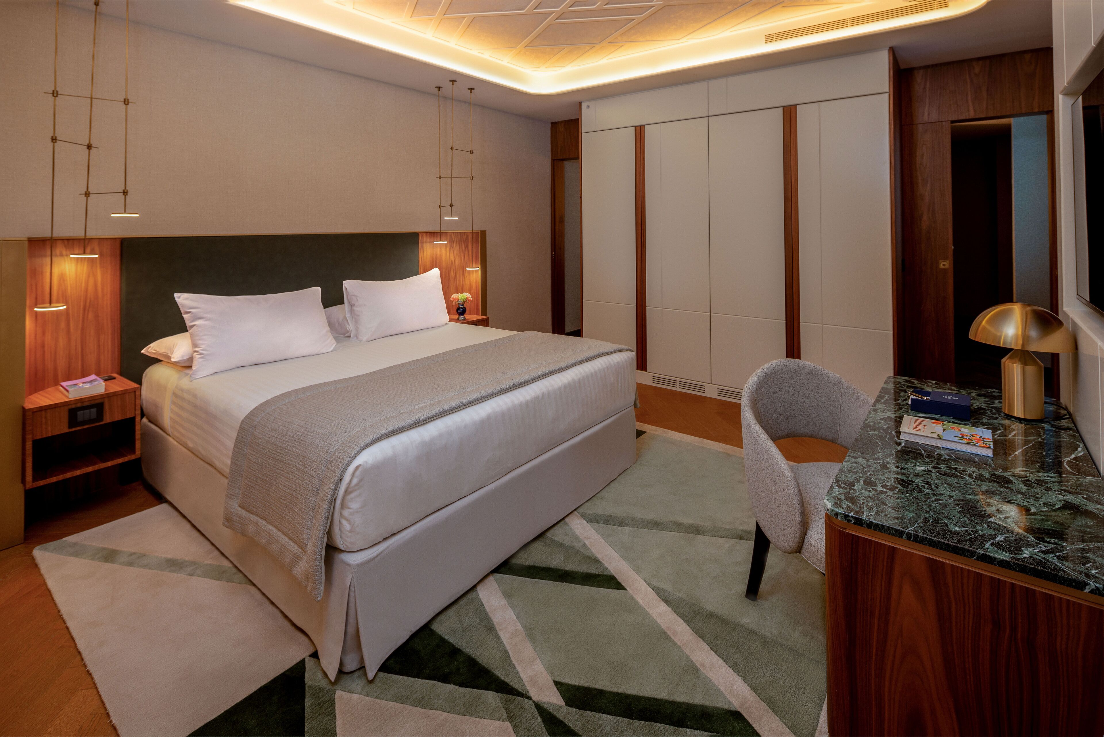 A modern hotel room with a large bed, bedside tables, a desk, and a chair.