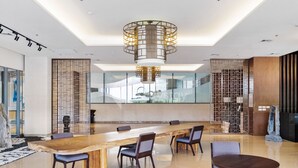 Une salle de conférence moderne, dotée d’une longue table en bois, de plusieurs chaises et d’un lustre circulaire original.