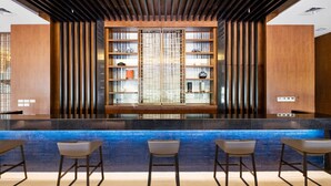 Un espace bar moderne avec un comptoir éclairé de lumière bleue et trois tabourets de bar.