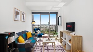 Un salon moderne avec un canapé, un fauteuil, une table basse et un téléviseur affichant l’interface de « Netflix ».