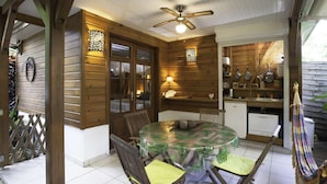 Um quarto de madeira aconchegante com uma mesa redonda e cadeiras, um ventilador de teto e uma área de cozinha com armários e uma pia.