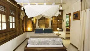 Quarto com cama de madeira, dossel e mesa de cabeceira com abajur.
