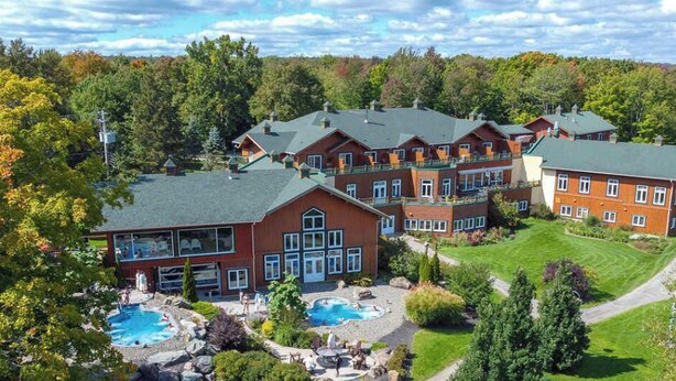 A resort with multiple buildings, outdoor swimming pools, and a well-maintained lawn.