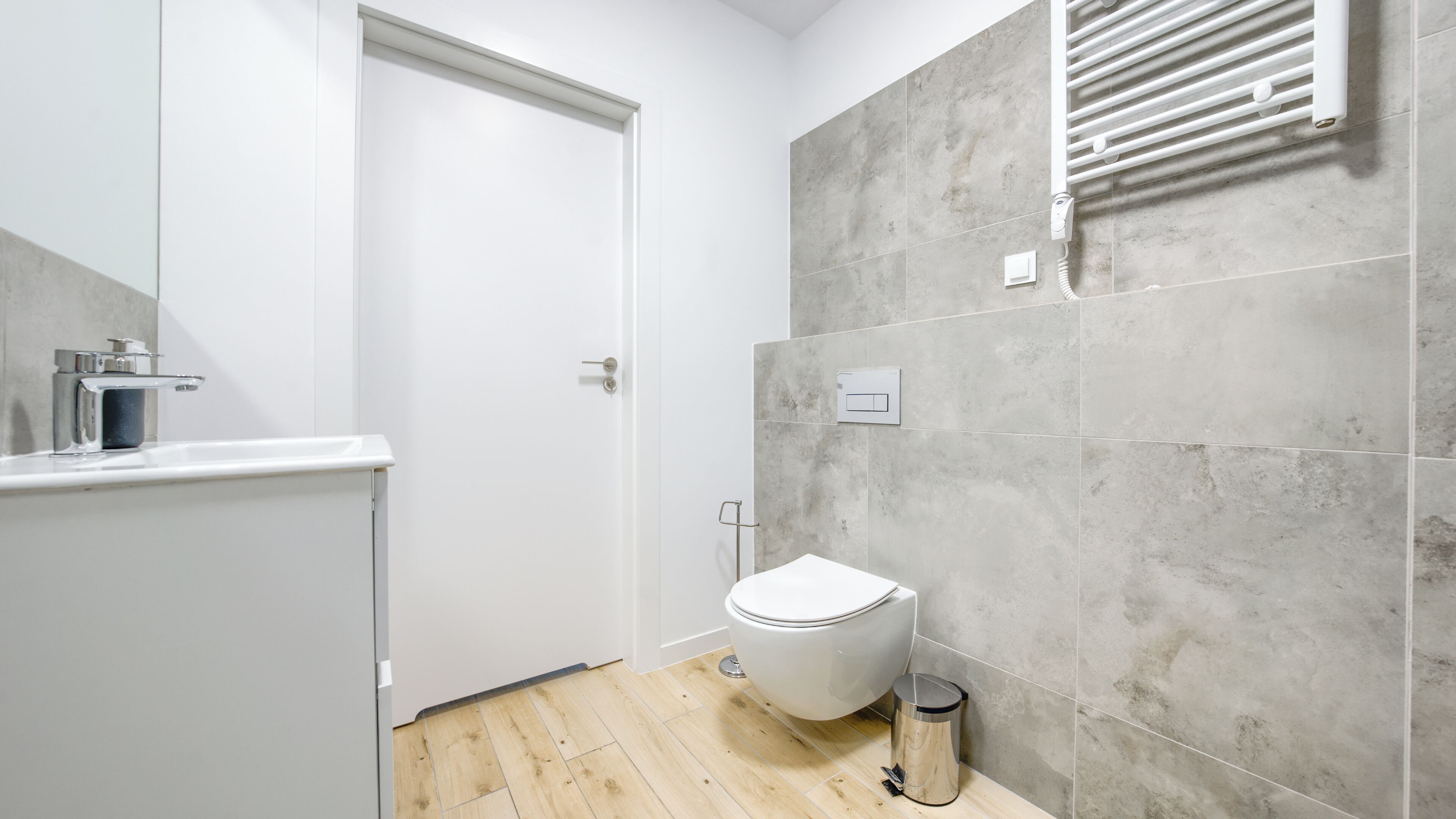A modern bathroom with a white toilet, a shower area, and a tiled wall.