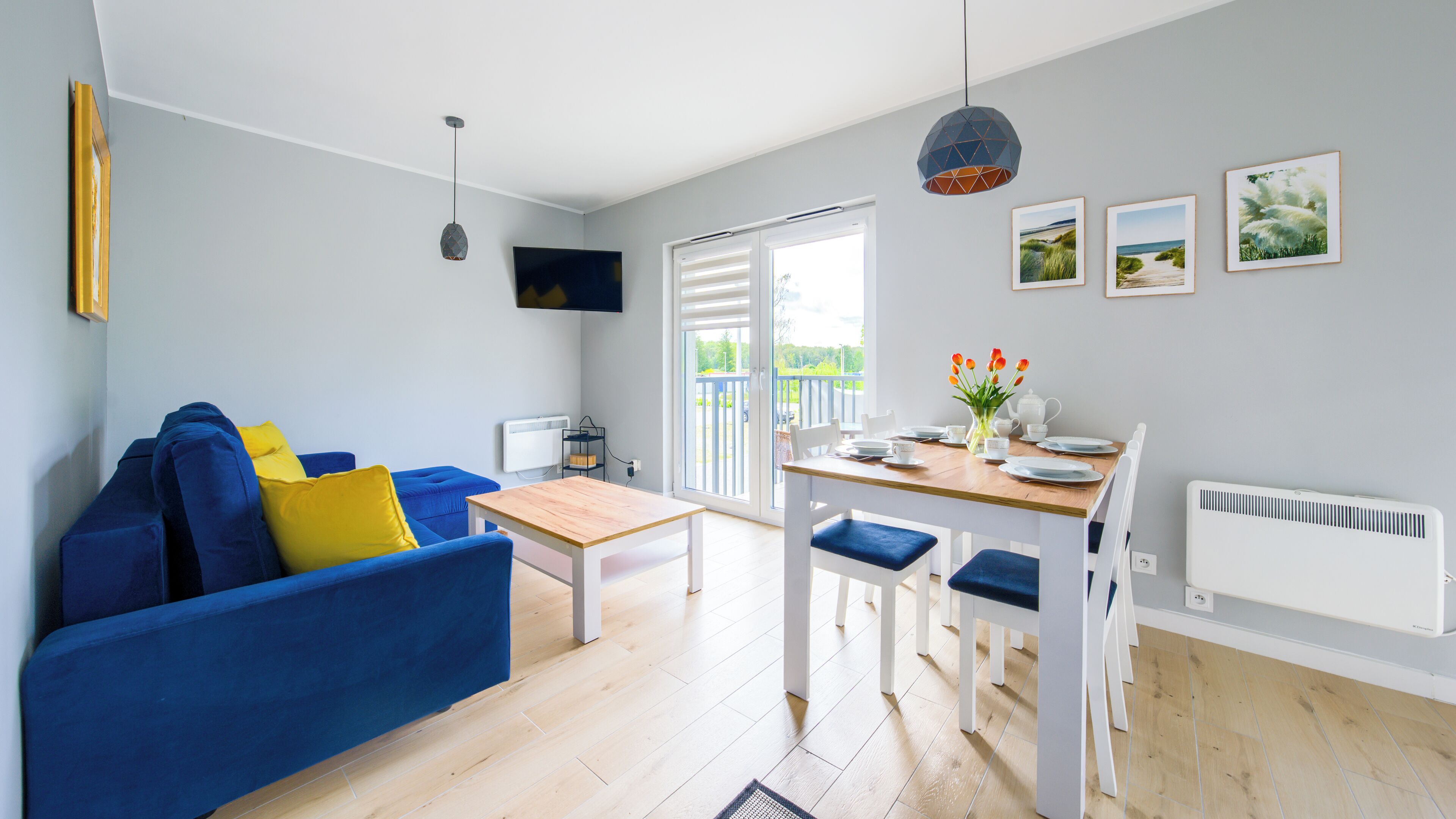 Ein modernes Wohnzimmer mit einem blauen Sofa, einem Holzesstisch und einer weißen Heizung.