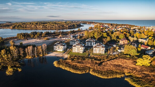 An aerial view of a lakeside town with a mix of residential and commercial buildings, surrounded by forested areas and a body of water.