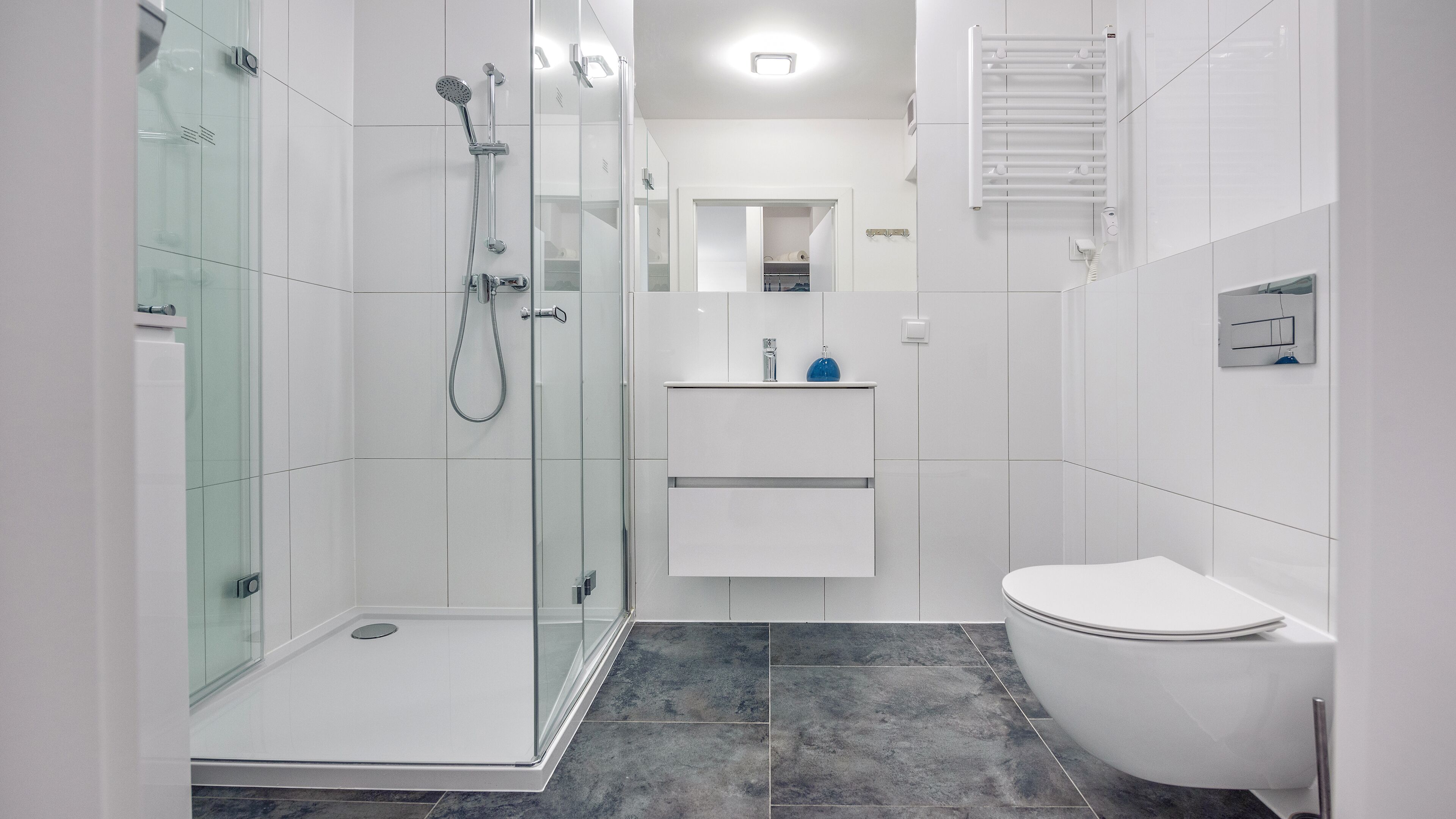 A modern bathroom with a glass-enclosed shower, a white sink with a mirror above, and a toilet.