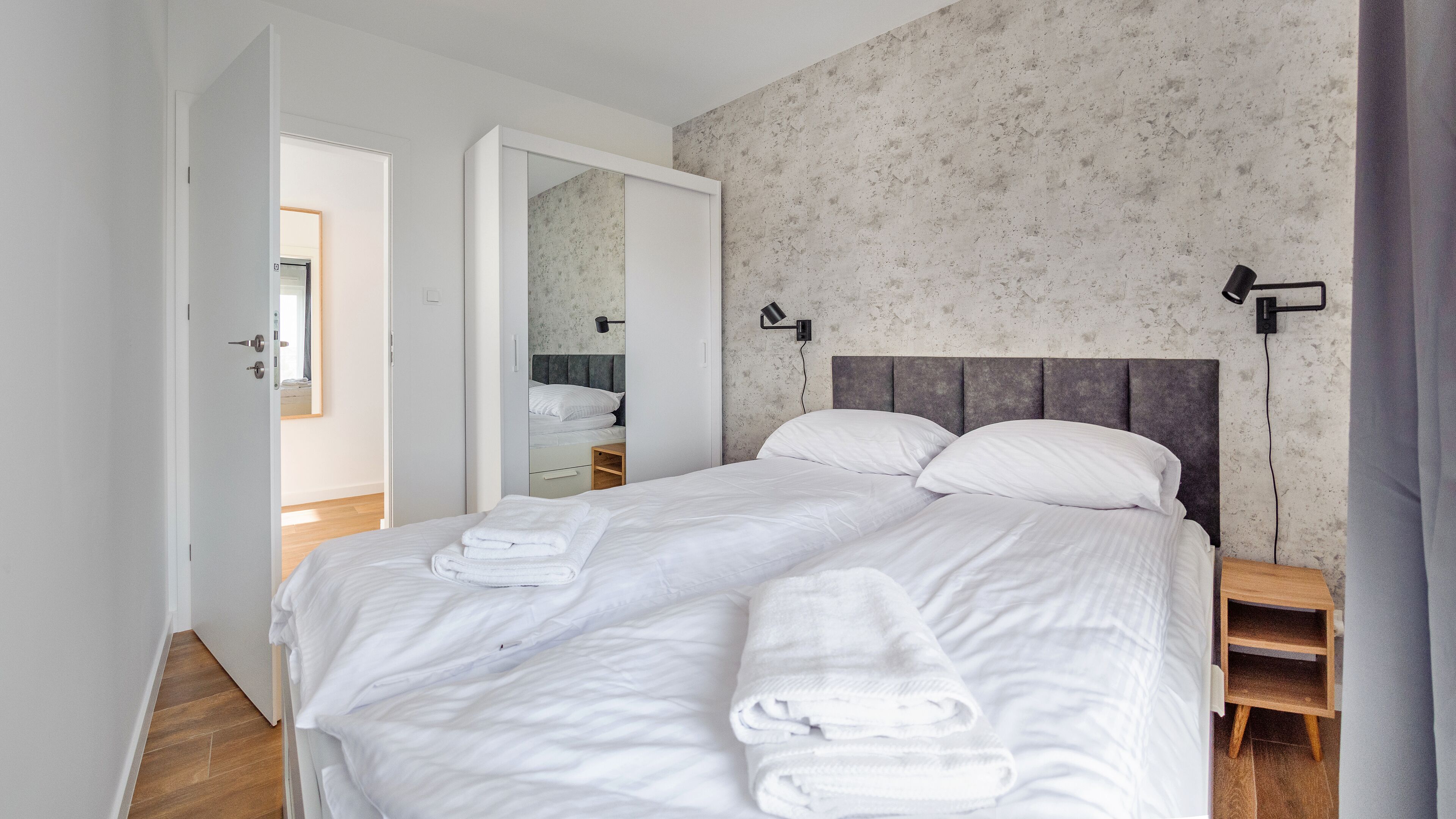Une chambre à coucher avec un grand lit, une table de chevet, un miroir et une armoire.
