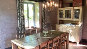 Un comedor con una mesa y sillas de madera, una araña y una ventana con cortinas.
