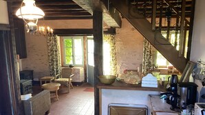 Una cocina rústica con escalera de madera, candelabro, mobiliario de mimbre y vistas al exterior.