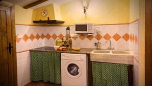 Une cuisine compacte équipée d’un lave-linge, d’un four à micro-ondes et d’un évier.