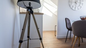 Un salon moderne avec un lampadaire, un coin repas comprenant une table et des chaises, et une grande horloge murale.