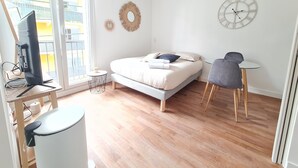 Une chambre moderne avec un lit, un bureau avec un ordinateur, une petite table ronde et une chaise.