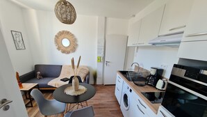 A compact kitchen with a washing machine, a coffee maker, and a sink. - Le Poulorio 7 -  T2 - Proche Gare * By Locly * (Lorient)