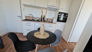 A compact kitchen with white cabinets, a built-in oven, and a coffee machine. - Le Poulorio 7 -  T2 - Proche Gare * By Locly * (Lorient)