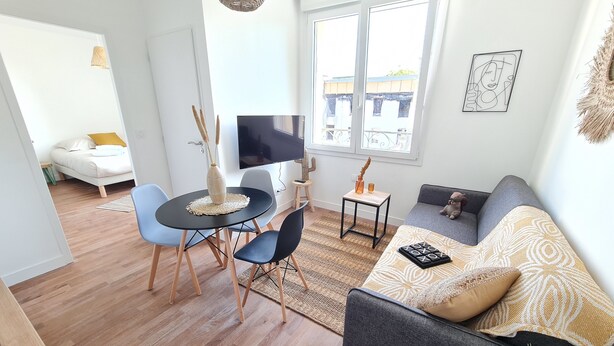 A modern living room with a sofa, a dining table, and a TV. - Le Poulorio 7 -  T2 - Proche Gare * By Locly * (Lorient)