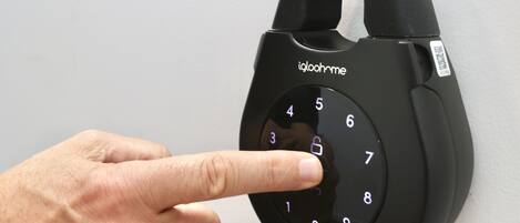 A hand pressing a number pad on a black electronic lock.