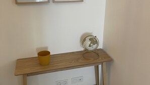 Une console en bois sur laquelle sont posés un globe terrestre et une tasse, ainsi qu’une prise électrique et deux tableaux encadrés accrochés au mur.