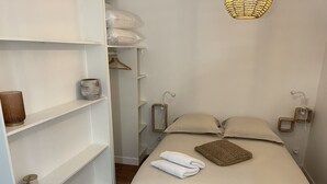 Une chambre à coucher bien rangée, avec un lit, des lampes de chevet, une table de chevet, un luminaire suspendu et une armoire.