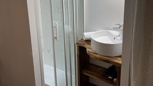Une salle de bain moderne avec une douche à parois de verre, un meuble-lavabo en bois et un lavabo blanc.