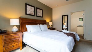 A neatly made bed with white linens, a wooden headboard, and two bedside lamps. There is a wooden nightstand with drawers and a lamp, and a framed map on the wall. - Near Disney: Townhouse w/ Resort Pool & Hot Tub (Kissimmee)