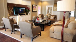 A living room with a television, two sofas, a coffee table, and a lamp. - Near Disney: Townhouse w/ Resort Pool & Hot Tub (Kissimmee)