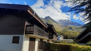 Un chalet traditionnel doté d’un balcon en bois, d’un petit porche et offrant une vue sur les montagnes.