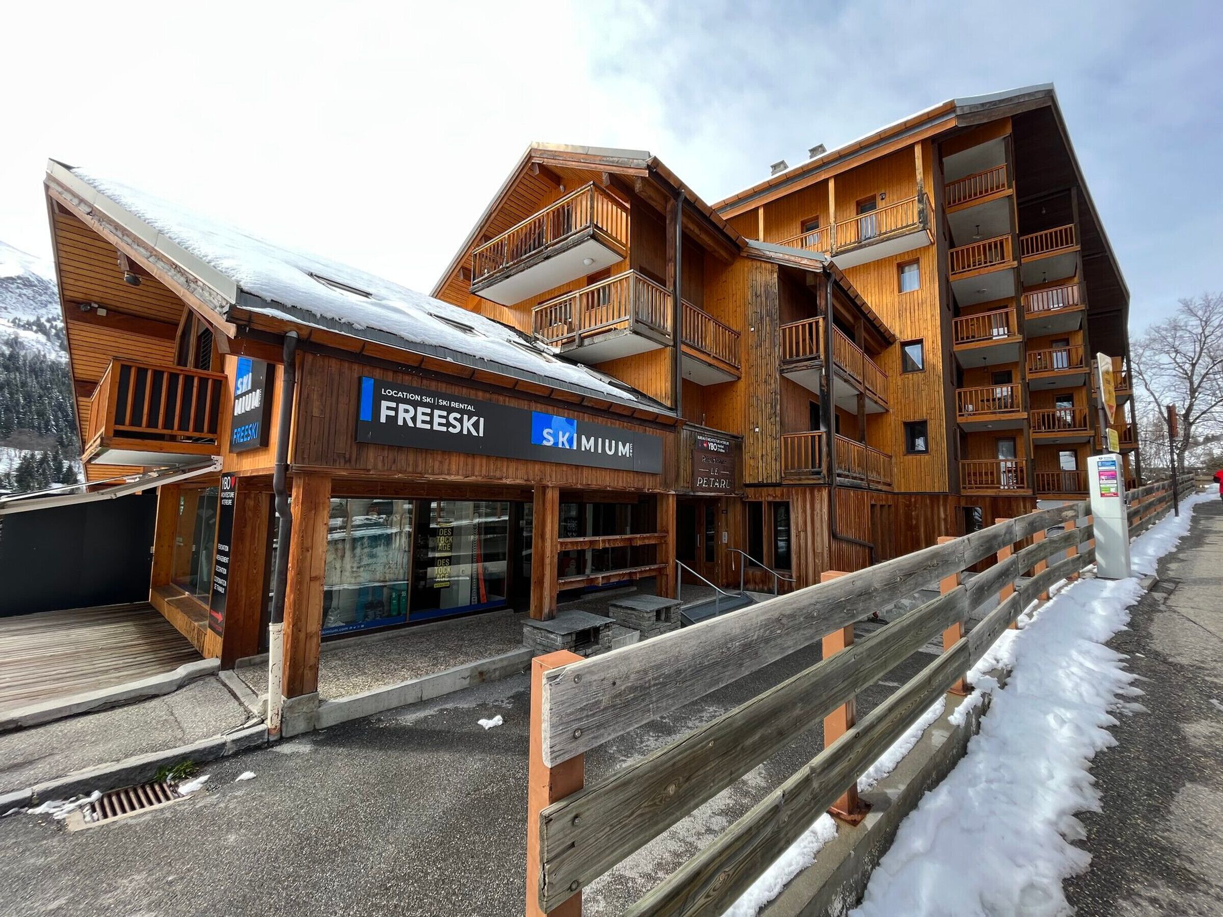 A wooden multi-story building with balconies, a ski rental sign, and a pet store.