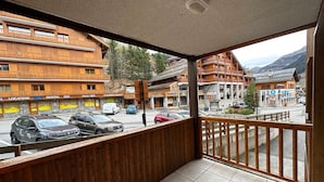 Ein Balkon mit Blick auf eine Bergstadt, mit Holzhäusern und geparkten Autos.