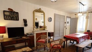 Una sala de estar con televisión, chimenea, mesa de comedor con mantel rojo, sofá y un espejo grande.
