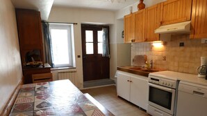 Una cocina con armarios de madera, estufa, lavaplatos y una mesa con mantel estampado.
