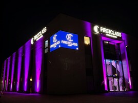 A building with illuminated signs reading "FIRSTCLASS" and "EVENT & HOTEL".