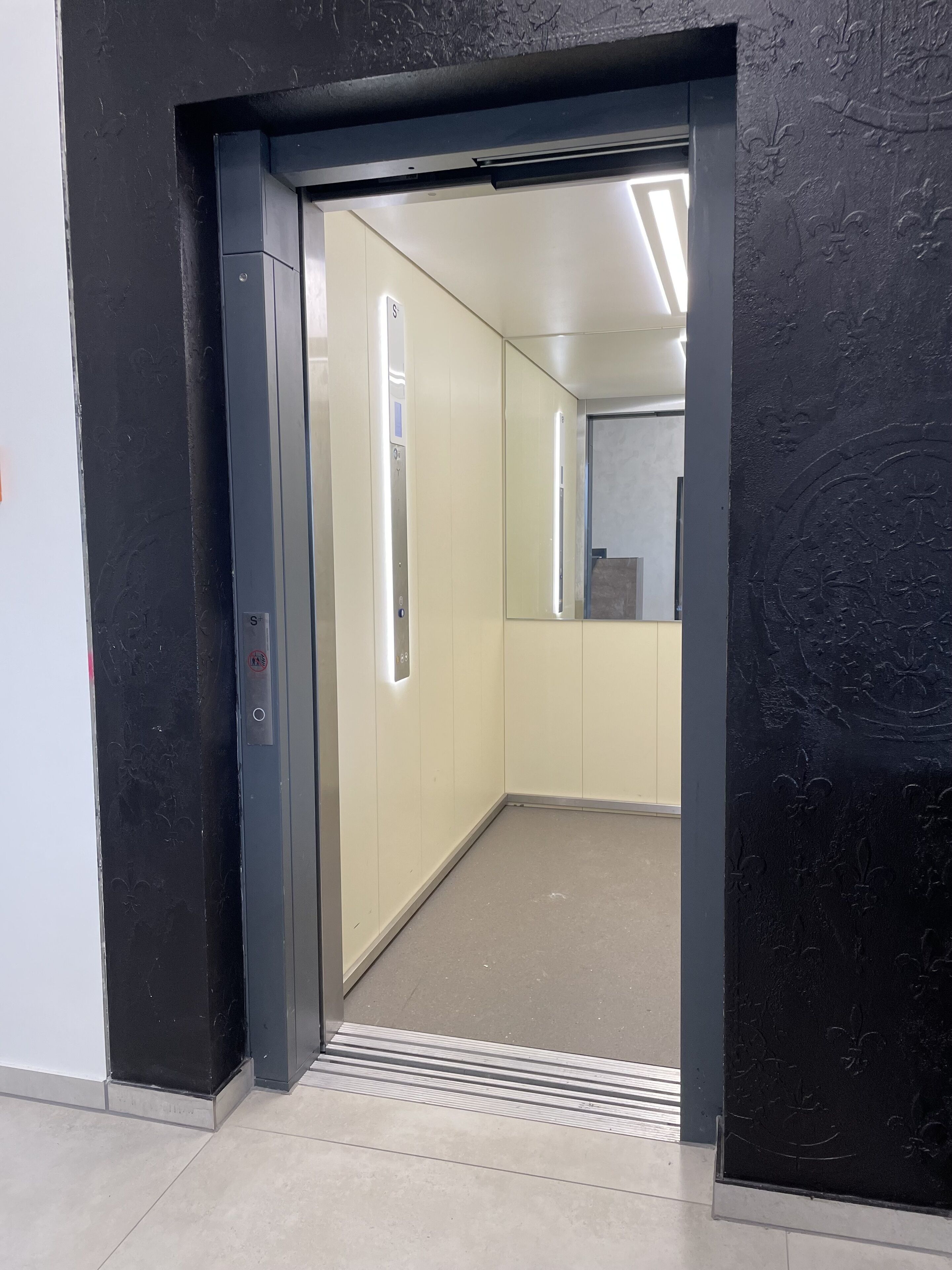 Un ascenseur doté d’une porte métallique et d’un panneau de commande avec un bouton.