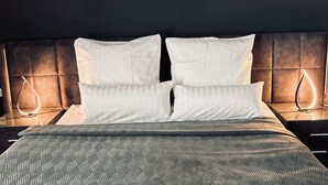 A neatly made bed with a patterned bedspread, two white pillows, and a headboard with a tufted design. - Firstclass Event & Hotel (Fuerth)