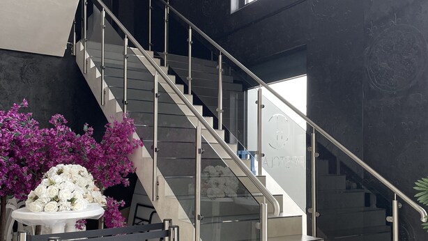 A modern staircase with glass railings and a white table with flowers. - Firstclass Event & Hotel (Fuerth)