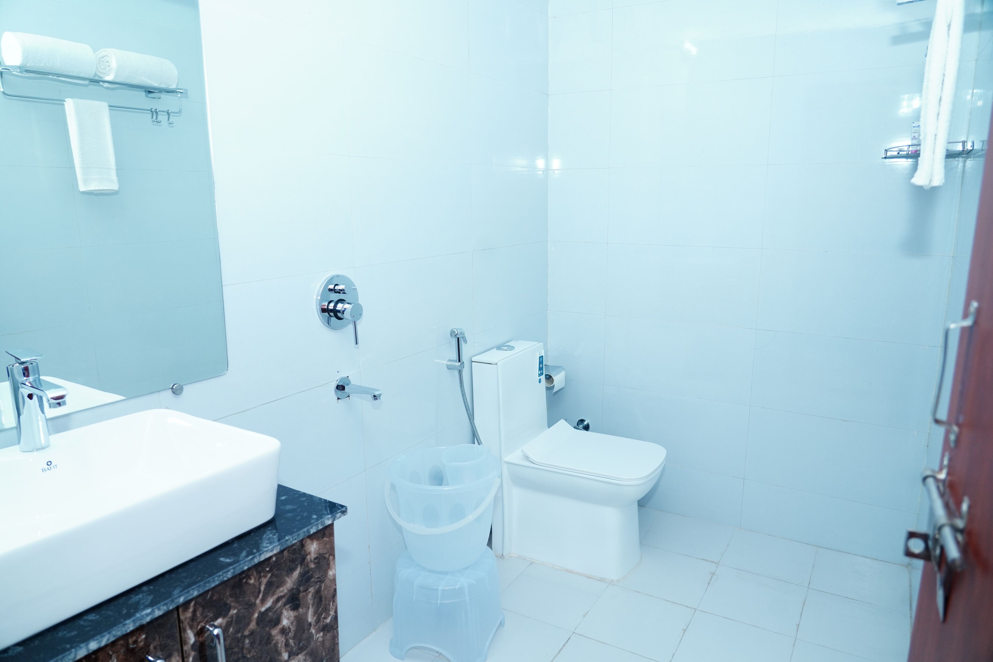 Une salle de bain avec un lavabo blanc, un miroir, des toilettes et une douche.