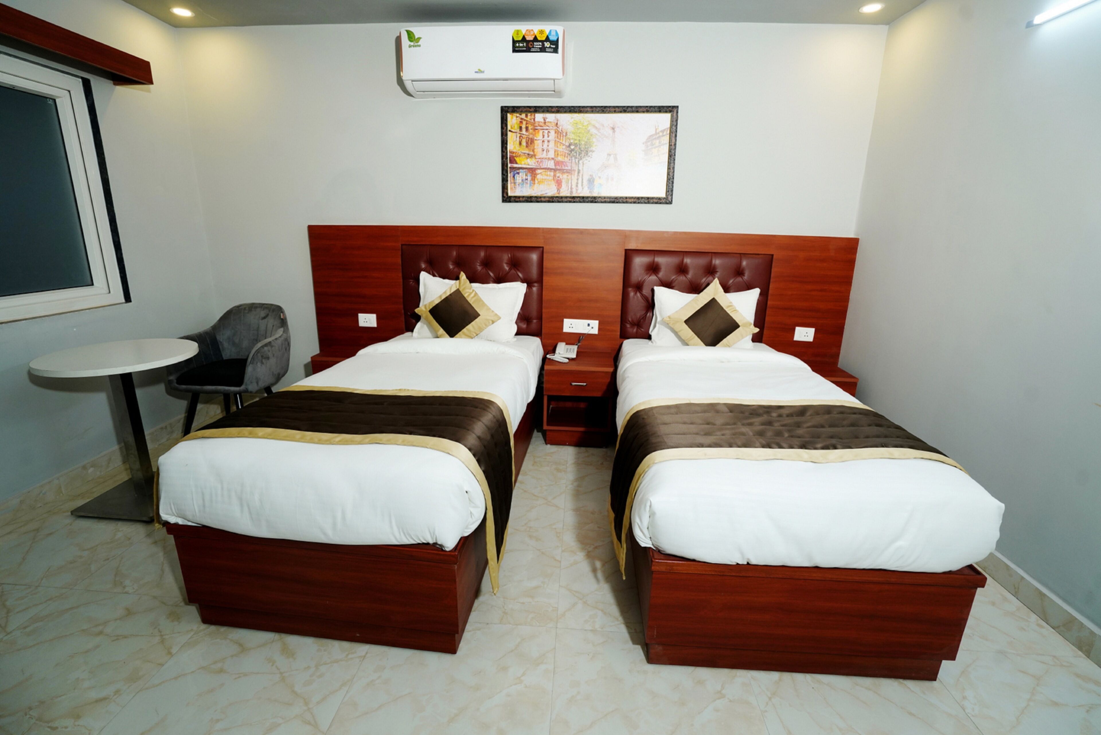 A hotel room with two beds, a small round table, and a chair.