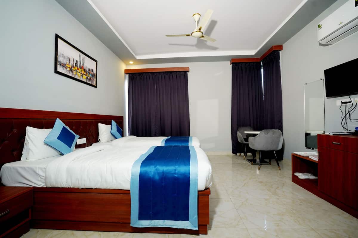 Una habitación de hotel con cama, escritorio, silla, televisión y ventilador de techo.